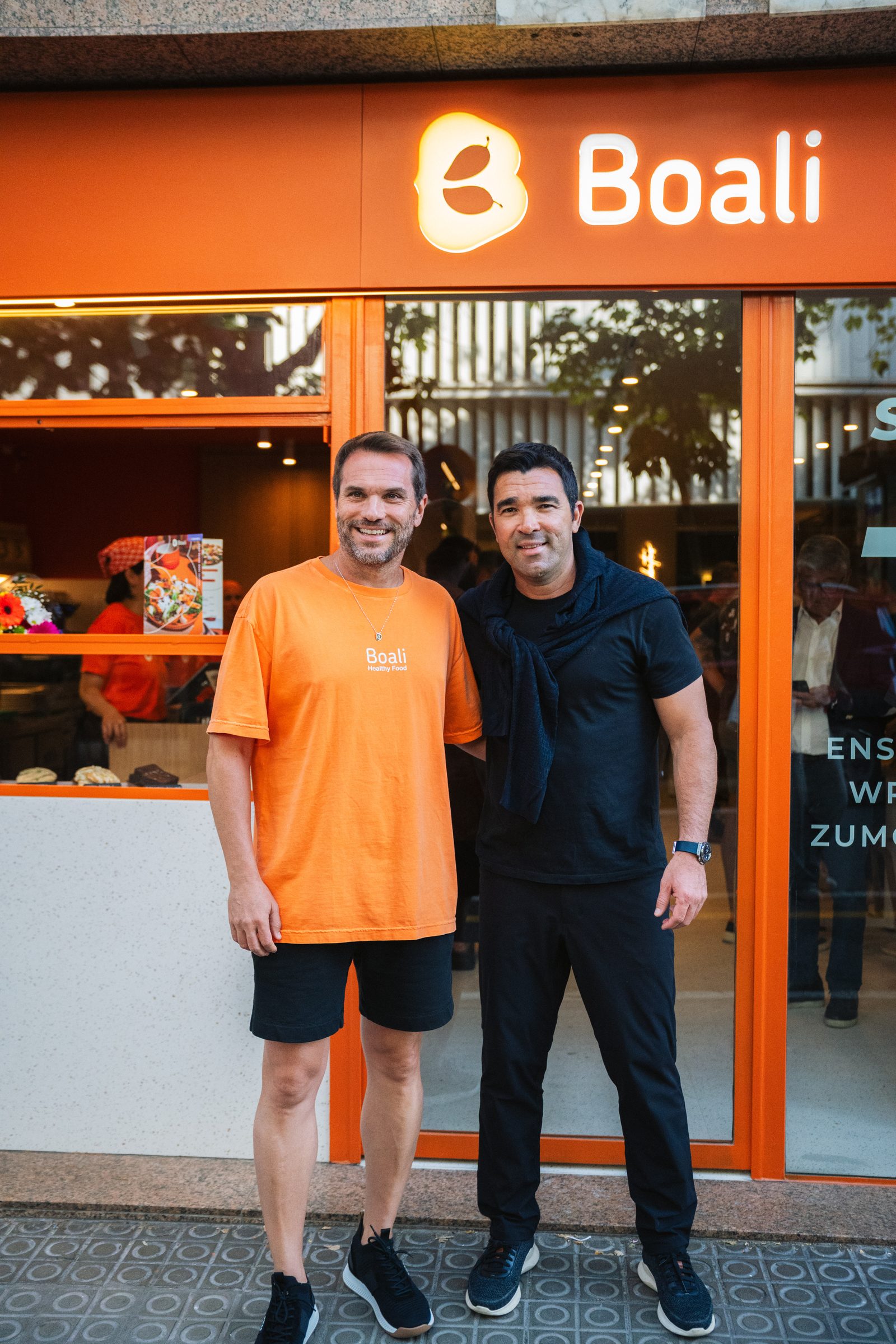 Dos socios de Boali frente a la fachada naranja de la tienda