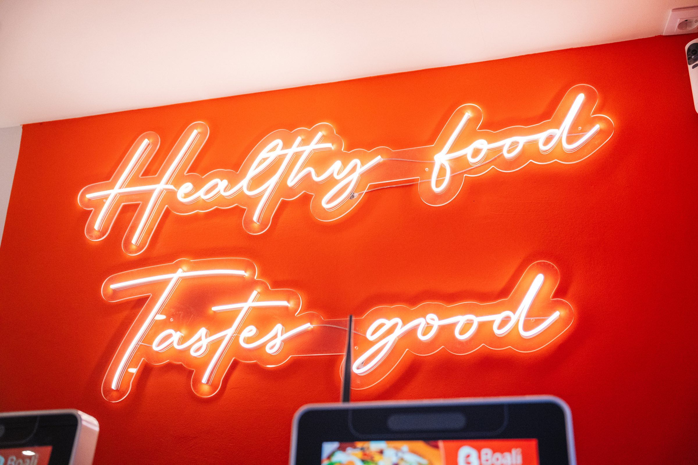 Letrero luminoso en la tienda: Healthy food Tastes good