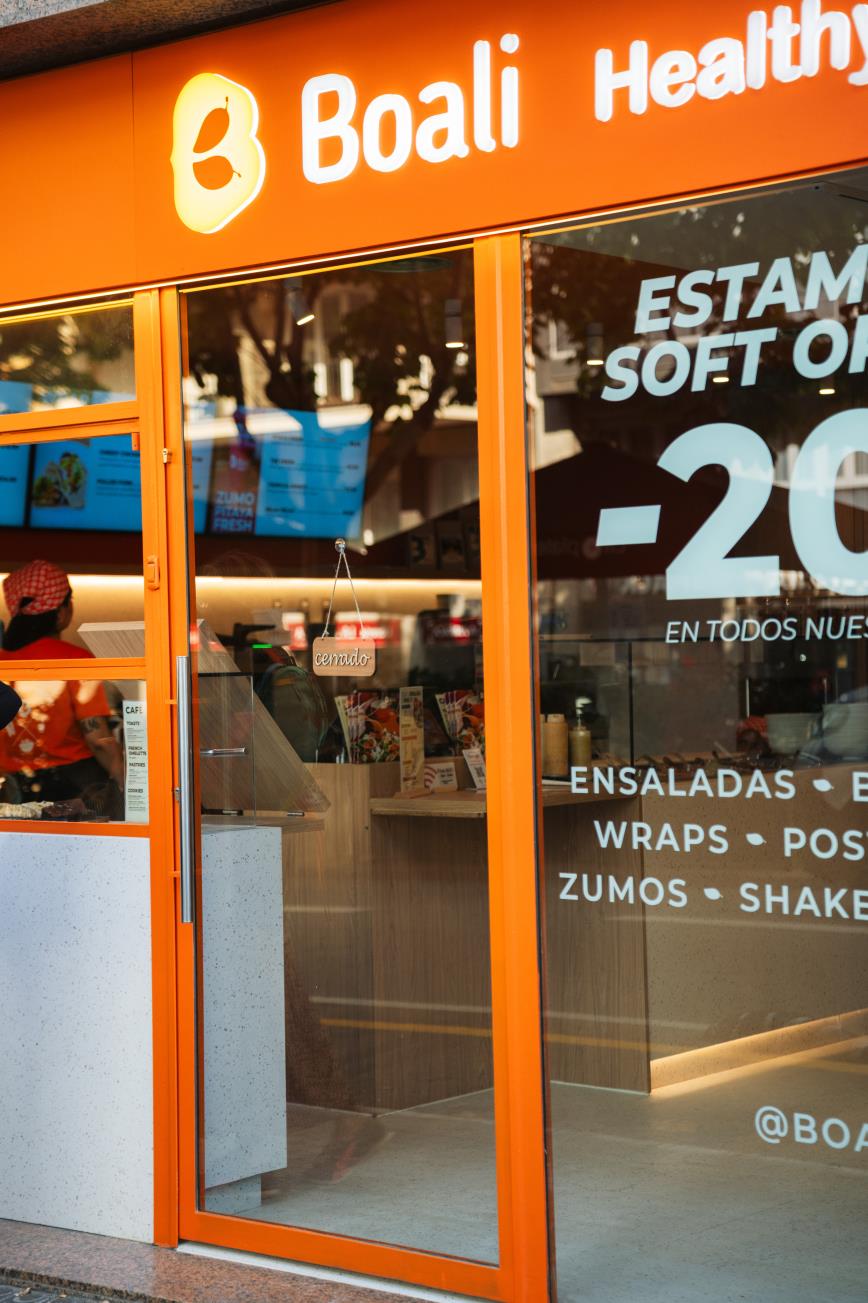 Entrada acristalada de Boali Via Augusta con el rótulo naranja